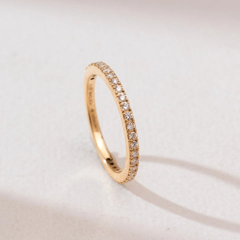 Angled view of the Timeless Full Circle Diamond Band crafted in 14KT yellow gold, showcasing a seamless circle of round brilliant diamonds in a delicate shared-prong setting.