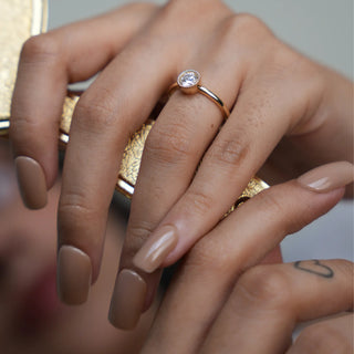 A close-up top view of an engagement female ring of size 12, modelled on a hand, crafted in a radiant 0.54-carat solitaire lab-grown diamond, meticulously set in a classic four-prong basket setting. The warm glow of the 14 KT yellow gold band weighing a total of 2.57 grams, complements the diamonds brilliance, creating a timeless and elegant piece of jewellery.