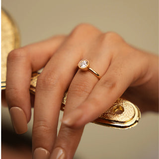 A close-up top view of an engagement female ring of size 12, modelled on a hand, crafted in a radiant 0.54-carat solitaire lab-grown diamond, meticulously set in a classic four-prong basket setting. The warm glow of the 14 KT yellow gold band weighing a total of 2.57 grams complements the diamond brilliance, creating a timeless and elegant piece of jewellery.