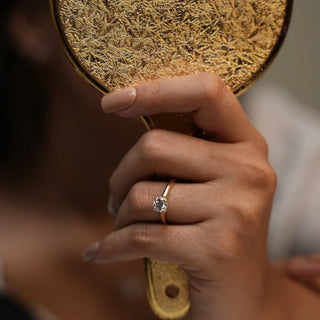 The front view of this female ring of size 12, worn by a model, features a brilliant 0.86-carat lab-grown diamond set in 14 KT yellow gold weighing a total of 2.89 grams. The solitaire diamond is the centrepiece, showcasing its brilliance and timeless elegance. In this view, the ring's exquisite design and sparkling diamond are highlighted, emphasizing its classic luxury and refined sophistication.