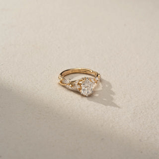 Side view of a pear-shaped diamond engagement ring in 14 KT Yellow Gold, featuring a pear-cut lab-grown diamond accented by marquise-shaped side diamonds in a nature-inspired band, displayed against a beige backdrop.