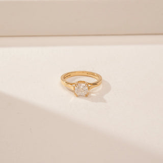 Close-up view of a 14KT Yellow Gold diamond ring with a square centre diamond and plain tapered band.
