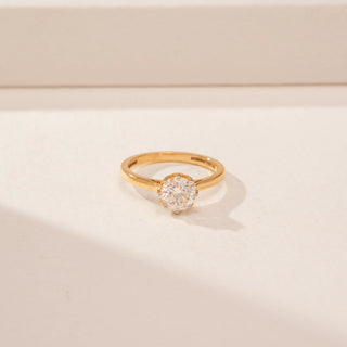 Close up view of a 14KT Yellow Gold diamond ring, featuring a round centre diamond in a scalloped setting.