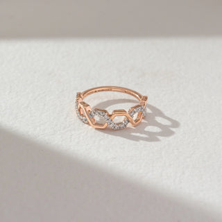Top angled view of geometric diamond band ring in rose gold, featuring hexagonal links with alternating lab-grown diamond-studded and plain segments. Set against a soft beige textured background.