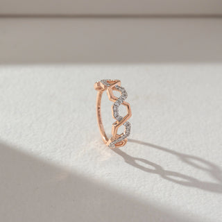 Side profile of geometric diamond band ring in rose gold, featuring hexagonal links with alternating lab-grown diamond-studded and plain segments. Captured against a soft beige textured background.