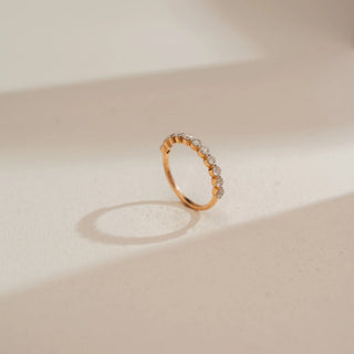 Side view of Reia’s 18 KT Rose Gold Classic Half Diamond Eternity Ring. It highlights the delicate band and the shimmering row of pavé-set round diamonds against a neutral backdrop.