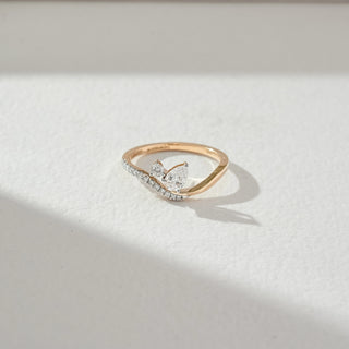 Top view of butterfly diamond ring in yellow gold, featuring pear-shaped lab-grown diamonds forming a delicate butterfly motif with a curved diamond-studded band. Set on a soft neutral surface, it reflects graceful brilliance.