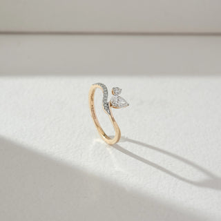 Side angled view of butterfly diamond ring in yellow gold, featuring pear-shaped and round lab-grown diamonds forming a delicate butterfly motif with a curved diamond-studded band. Set on a soft neutral backdrop, it highlights elegance.