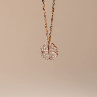 Front view of Reia’s 14 KT Rose Gold Lucky Clover Diamond Heart Pendant. Captured on a pink backdrop, it highlights the heart-shaped motifs arranged into a four-leaf clover.