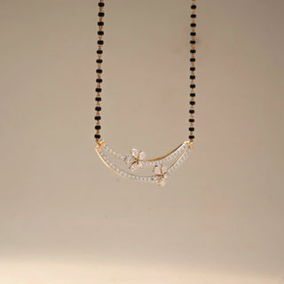 Front view of a yellow gold lab-grown diamond mangalsutra featuring a curved pavé diamond pendant with floral diamond motifs on a classic black bead chain, displayed on a neutral background.
