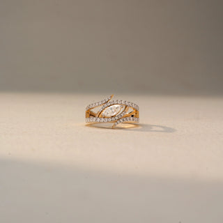 Front view of a marquise diamond wrap ring in 14 KT Yellow Gold, featuring a marquise-cut lab-grown diamond framed by intertwined pavé-set diamond bands in a layered open design, displayed against a beige backdrop.
