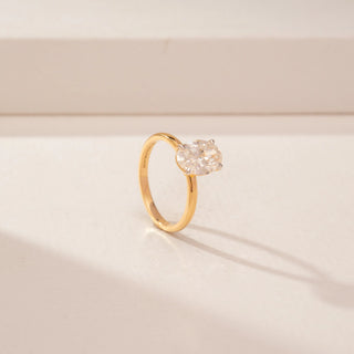 Angled view of a 14KT Yellow Gold diamond ring, featuring an oval-cut centre diamond and a plain gold band.