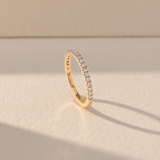 Side view of Pavé Diamond Band Ring in 14KT Yellow Gold, featuring a continuous row of round lab grown diamonds in pavé setting. Set on a beige backdrop, the design highlights structure and brilliance.
