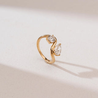 Angled view of Serpentine Duo Diamond Ring in 14KT yellow gold, featuring a round and pear-cut diamond set on a flowing S-shaped Toi et Moi bypass band.