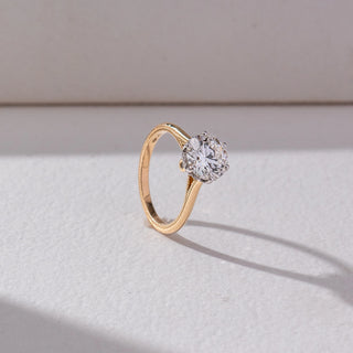 Side view of Round Solitaire Diamond Ring in 14KT Yellow Gold, featuring a centred round lab grown diamond in prong setting. Set on a beige backdrop, the design highlights structure and classic elegance.
