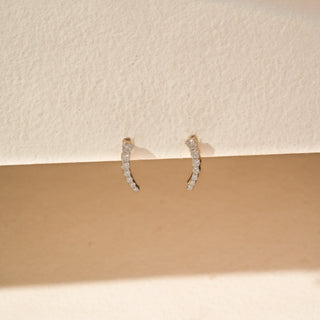 Front view of curved diamond drop earrings in 14KT Yellow Gold, featuring a row of round diamonds.