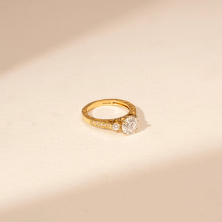 Side view of a 14KT Yellow Gold diamond ring with a round centre diamond and diamond-set shoulders.