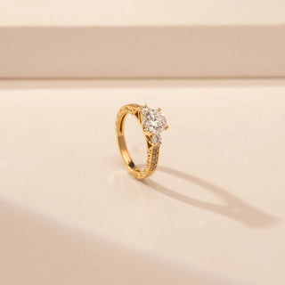 Angled view of a 14KT Yellow Gold diamond ring with a round centre diamond and diamond-set shoulders.