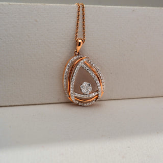 Close-up front view of a rose gold teardrop pendant necklace featuring pavé-set diamond curves and a round diamond cluster centerpiece, displayed against a soft neutral backdrop.