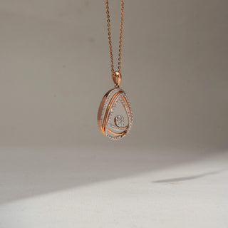 Side view of a rose gold teardrop pendant necklace featuring pavé-set diamond curves and a round diamond cluster centerpiece, suspended from a delicate chain.