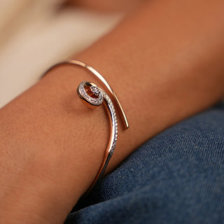 A close-up view of an elegant female bracelet of size 2.4 with a spring lock, modelled on a hand, featuring a slim rose gold bracelet with an eye-catching diamond-studded spiral weighing 8.15 grams, modelled on a hand. The 14 KT rose gold setting showcases 0.38 carats of lab-grown diamonds, creating a sleek, modern design that balances minimalism with luxury against a clean white backdrop.