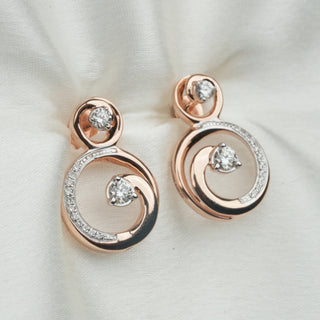 The top view of female Earrings of A captivating close-up showcasing the earrings' unique circular design secured through a bombay screw. The 14 KT rose gold setting provides a warm foundation for the sparkling 0.54 carats of lab grown diamonds, arranged in a delicate circular pattern within a larger circle. The earrings exude a modern elegance, perfect for adding a touch of sophistication to any outfit.