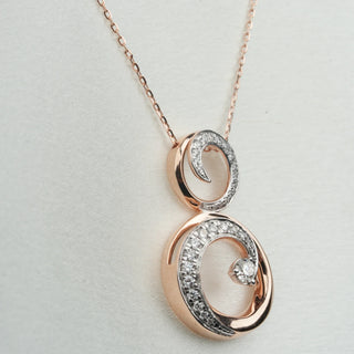 A close-up side view of a female 14 KT female rose gold necklace secured through a spring lock of size 16 on a white background, featuring two interlocking circular pendants, the larger open circle and the smaller solid circle encrusted with round brilliant lab-grown diamonds totalling 0.638 carats set in a pavé style and total weight is 7.4 grams. The interconnected circles create an elegant yet modern infinity-inspired motif suspended from a rose gold cable chain necklace