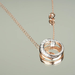 A mirror reflection of the side view of a female necklace crafted in 14 KT rose gold of size 20 secured through a spring lock. The necklace features a graceful swirl design with two central diamonds, adding a touch of brilliance. The total weight of the necklace is 6.22 grams and the total weight of the diamonds is 0.602. The pendant is displayed on a mirror background, enhancing the elegance and sparkle of the lab-grown diamonds through reflections that highlight the intricate craftsmanship.