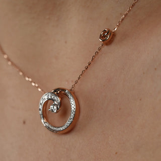 Side view on the neck of the model of a Dainty Swirl Diamond Pendant female Necklace of size 20 crafted in 14 KT female rose gold secured through a spring lock.  The total weight of the necklace is 6.22 grams and the total weight of the diamonds is 0.602. The necklace features a graceful swirl design with two central diamonds, adding a touch of brilliance. The female necklace is displayed on a mirror background, enhancing the elegance and sparkle of the diamonds