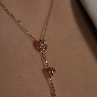 A close-up photo of a woman's neck wearing a delicate rose gold necklace adorned with two interconnected circles, each featuring a sparkling diamond in the centre. This elegant piece is perfect for both casual and formal occasions, adding a touch of luxury. The image features the close-up front view of a swirling 14 KT Diamond Necklace, adorned with 0.21 carats of lab-grown diamonds, elegantly worn on the neck of the model of size 16 secured through a spring lock weighing a total of 3.28 grams