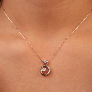 A view of an exquisite female pendant, modelled on a neckline, featuring a circular pendant crafted in 14 KT rose gold  weighing 3.21 grams. The pendant displays an interlocking double circle design, with the outer rose gold circle elegantly embracing an inner circle pavé-set with shimmering lab-grown diamonds totalling 0.445 carats. This eternal knot motif is suspended from a delicate rose gold chain necklace, allowing a minimalist look.