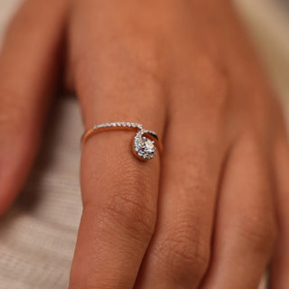 A front view of a ring of a size 12, on a model's hand, featuring an elegant infinity-inspired twist design in 14 KT rose gold. It showcases a graceful spiral shape encrusted with pavé-set lab-grown diamonds totalling 0.28 carats and the product weight being 2.41 grams. The twisted form creates a seamless and feminine look, while the rose gold metal provides a warm, flattering tone complemented by the brilliance of diamond accents.