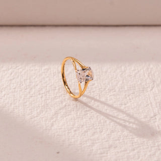 Side view of solitaire diamond ring in yellow gold, featuring a centred princess-cut lab-grown diamond set on a split shank band. Placed on a textured beige surface, the design casts a soft elongated shadow.
