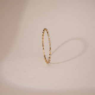 This is a classic yellow gold bangle size 2.5 features multiple lab grown diamonds of EF color and VVS clarity, totaling a 1.32 carats. The largest single stone measure 0.051, all balanced beutifully across totaling weight of 9.707 carats.The bangle is signature piece for those who appreciate elelvated minimalism.The top angle view of the bangle against the badge background on a bangle holder highlights the elegance and minimilist approach of the bangle.