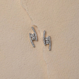 Captured from a top view on a textured beige paper background, a pair of 14 KT yellow gold diamond stud earrings gleam with minimalist sophistication. Designed with a modern arc silhouette, each piece features pavÃ©-set EF-color round diamonds in VVS clarity, totaling 0.40 carats. Weighing 1.875 grams gross and 1.795 grams net, these studs offer lightweight elegance perfect for everyday polish or subtle formal charm. 