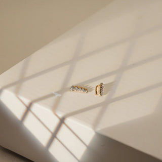 Placed on a softly illuminated ivory pedestal with crisscrossing natural light shadows, a pair of 14 KT yellow gold ear climber earrings is presented in a refined side angle. Each earring features a rising arc of EF-color, VVS-clarity round diamonds totaling 0.310 carats, tapering gracefully in size to accentuate the earâ€™s curve. The minimal gold framework adds warmth and modernity, enhancing the delicate shimmer of the stones. With a gross weight of 0.678 grams and a net weight of 0.616 grams.