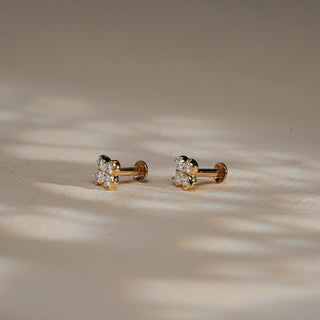 Side-angle view of Reia's Diamond Cluster Flower Stud Earrings on a textured cream background, emphasizing the symmetrical design, South screw back, and the graceful blend of 18KT gold and EF-VVS diamonds. Ideal for refined daily elegance.