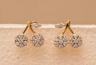 Gold earrings with diamond-like stones on a beige background