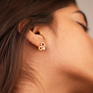 A side view of a pair of three-tone female stud earrings secured with a bombay screw, modelled on an earlobe, with an interlocking geometric design. The earrings are crafted from 14 KT multi colour gold (yellow, white, and rose gold) and feature lab-grown diamonds totalling 0.49 carats set in a pavé style with a total weight of 3.08 grams. The interlocking circles form an infinity symbol motif, creating an elegant and timeless look.