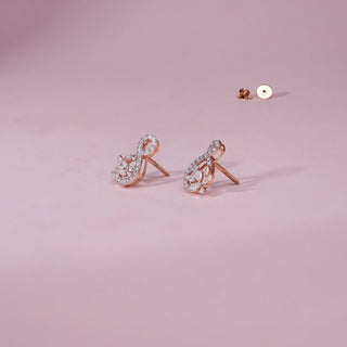 A close-up view of a pair of radiant 18 KT rose gold drop earrings, weighing 3.1g, showcasing their intricate clusters of 0.730 carats of luminous marquise-shaped EF VVS diamonds. The earrings are positioned on a light beige textured fabric, creating soft shadows, with a blurred light background, highlighting their detailed craftsmanship and continuous brilliance.