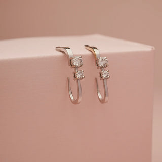 Side angle of Reia 18KT White Gold Modern Diamond Hoop Drop Earrings featuring two EF VVS round brilliant diamonds each, designed with a sleek drop-hoop silhouette for modern elegance.