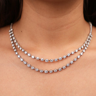 Front view of a Layered Lab Grown Diamond Charm female Necklace crafted in 14 KT White Gold,  featuring a total of 13.43 carats of diamonds and the weight of the product being 41.47 grams of size 24. The necklace presents two delicate chains adorned with round-cut diamonds, creating a sparkling and celestial effect on the model's neck secured with a S Hook Lock .