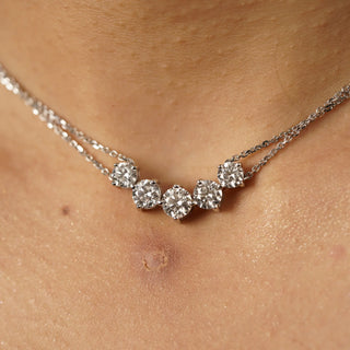 Photographed on a model, the Close-up view of an elegant female necklace weighing 5.57 grams featuring five brilliant-cut diamonds totalling 2.54 carats with a solitaire of 0.62 carats, set in a graceful curved line along a delicate 14 KT white gold chain on a white background of size 14 secured with a spring lock . The graduated sizes of the diamonds create a subtle sparkle effect, with the centre stone slightly larger