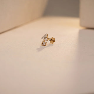 A delicate 14 KT yellow gold nose pin, gross weight 0.325g, featuring a single, brilliant round EF VVS diamond of 0.080 carats set in a classic stud design with a south screw. The nose pin is displayed on a textured dark surface, with soft lighting emphasizing its subtle sparkle and fine craftsmanship.