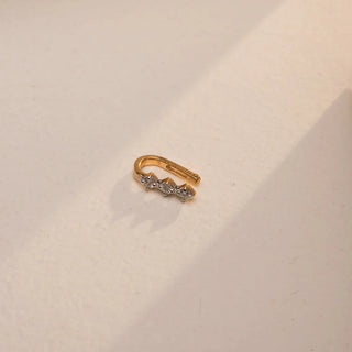 A tiny, elegant 18 KT yellow gold nose pin, gross weight 0.47g, featuring a single, brilliant round EF VVS diamond of 0.060 carats set in a classic stud design. The nose pin is displayed on a textured dark surface, with soft lighting emphasizing its delicate sparkle and fine craftsmanship.