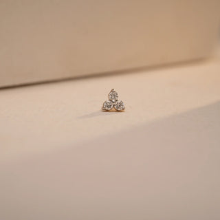 A tiny, dazzling 14 KT yellow gold nose pin, gross weight 0.253g, designed with a prominent 0.060 carat round EF VVS diamond. The nose pin is presented on a textured dark surface, with a blurred background, drawing focus to its elegant design and singular diamond
