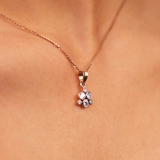 Suspended from a fine rose gold chain, this charming pendant showcases a delicate cluster of sparkling round stones, arranged like a petite floral motif that catches the light beautifully with every subtle movement.
