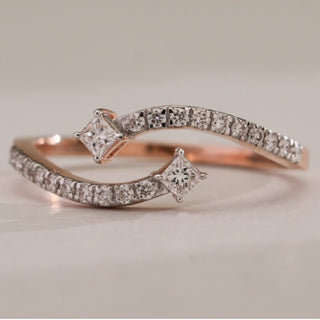 Close-up of Curved Diamond Twirl Ring in 14KT Rose Gold, featuring pavé-set EF VVS diamonds and two princess-cut diamonds at each end, totalling 0.24 carats.