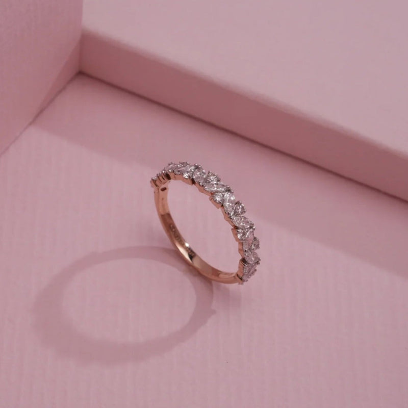 A delicate 14 KT rose gold ring, gross weight 1.617g, featuring a central marquise-shaped cluster of brilliant EF VVS diamonds, totaling 0.670 carats, set on a slender, polished band. The ring is angled slightly on a soft, dark textured surface, with subtle lighting highlighting its intricate detail and sparkle.