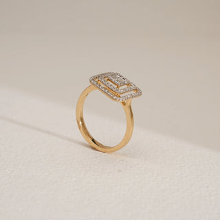 Regal Geometry Cocktail Diamond Ring in 18KT Yellow Gold, featuring layered square frames set with baguette and round-cut diamonds, captured from a side profile angle on a beige textured surface with soft shadows.